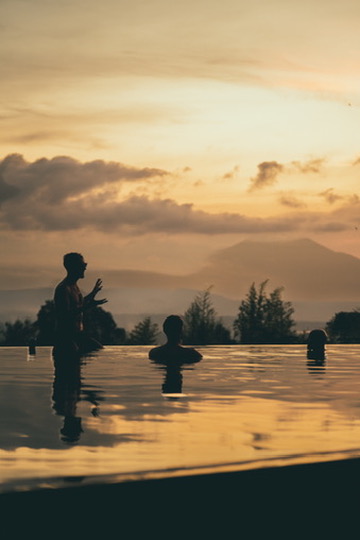 Sunset infinity-pool conversation with mountains beyond