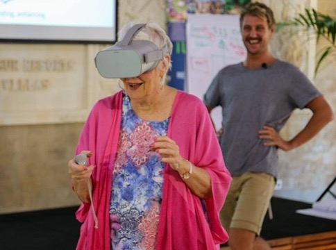 Elder guest laughing in VR headset during a workshop